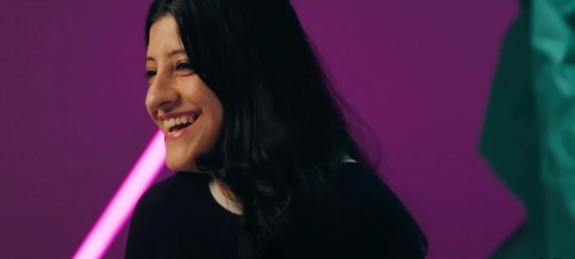 A smiling Deloitte colleague in front of a purple backdrop
